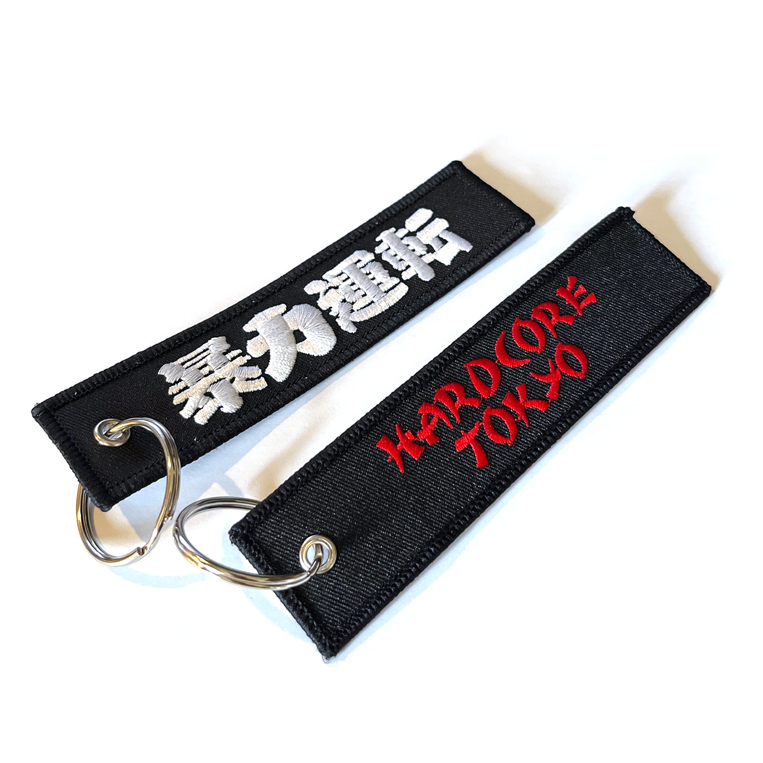 Two black fabric keychains with text on a Black background