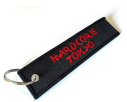 Black keychain with red text 'Hardcore Tokyo' on a white background