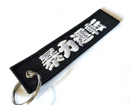 Black keychain with silver text on a white background