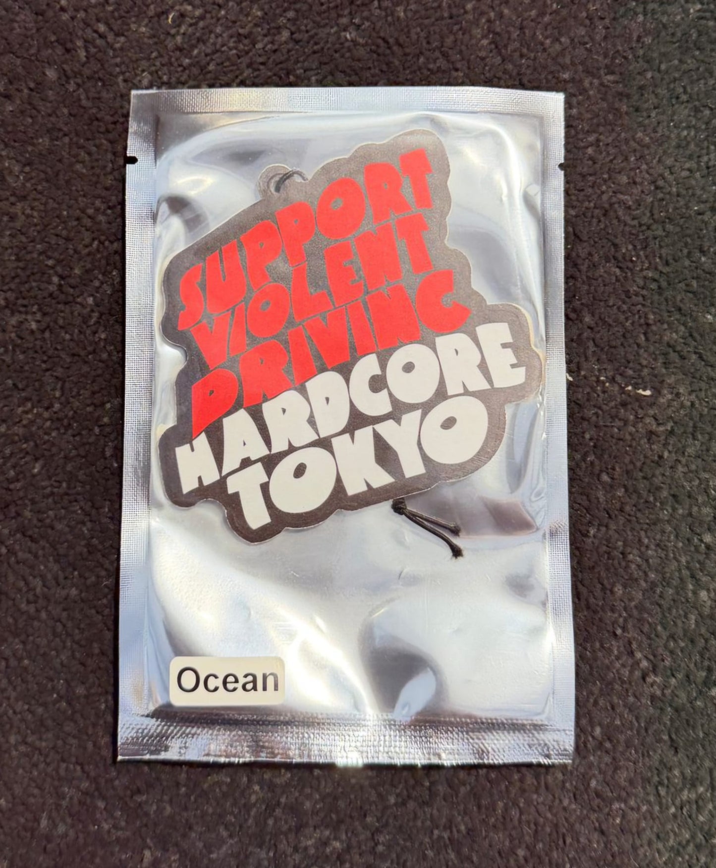 Silver foil packet with text 'Support Violent Driving Hardcore Tokyo' on a dark textured background
Hardcore Tokyo Wave Logo Air Freshener with an Ocean Flavour
